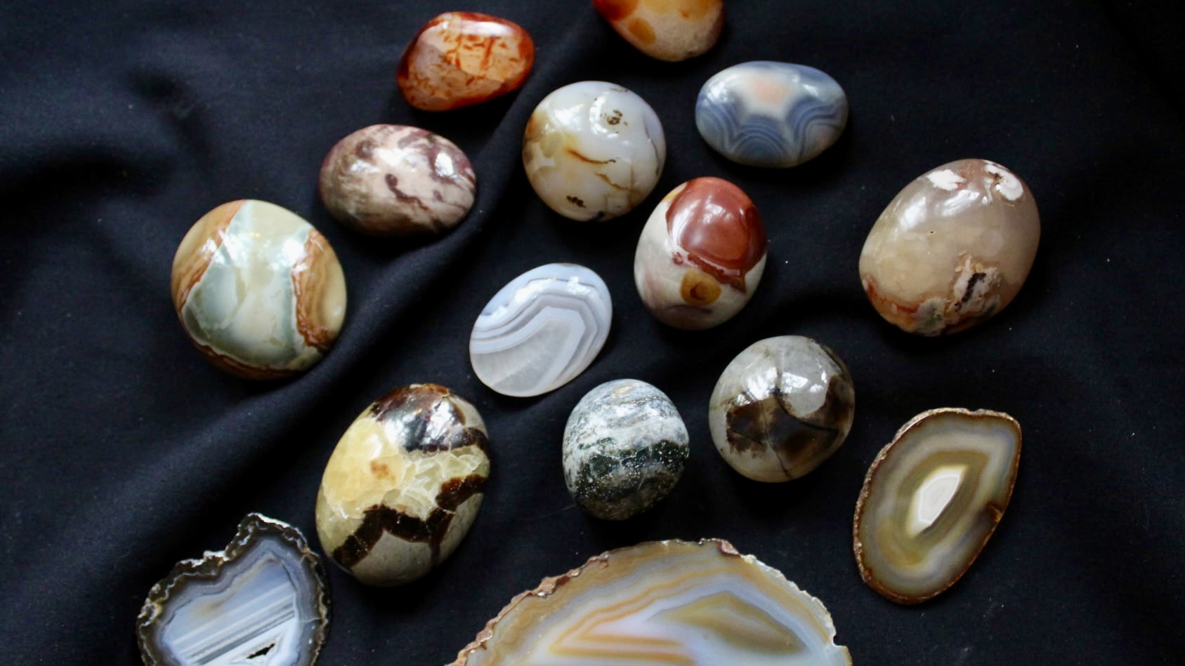 image of several polished rocks in various colors on a black background