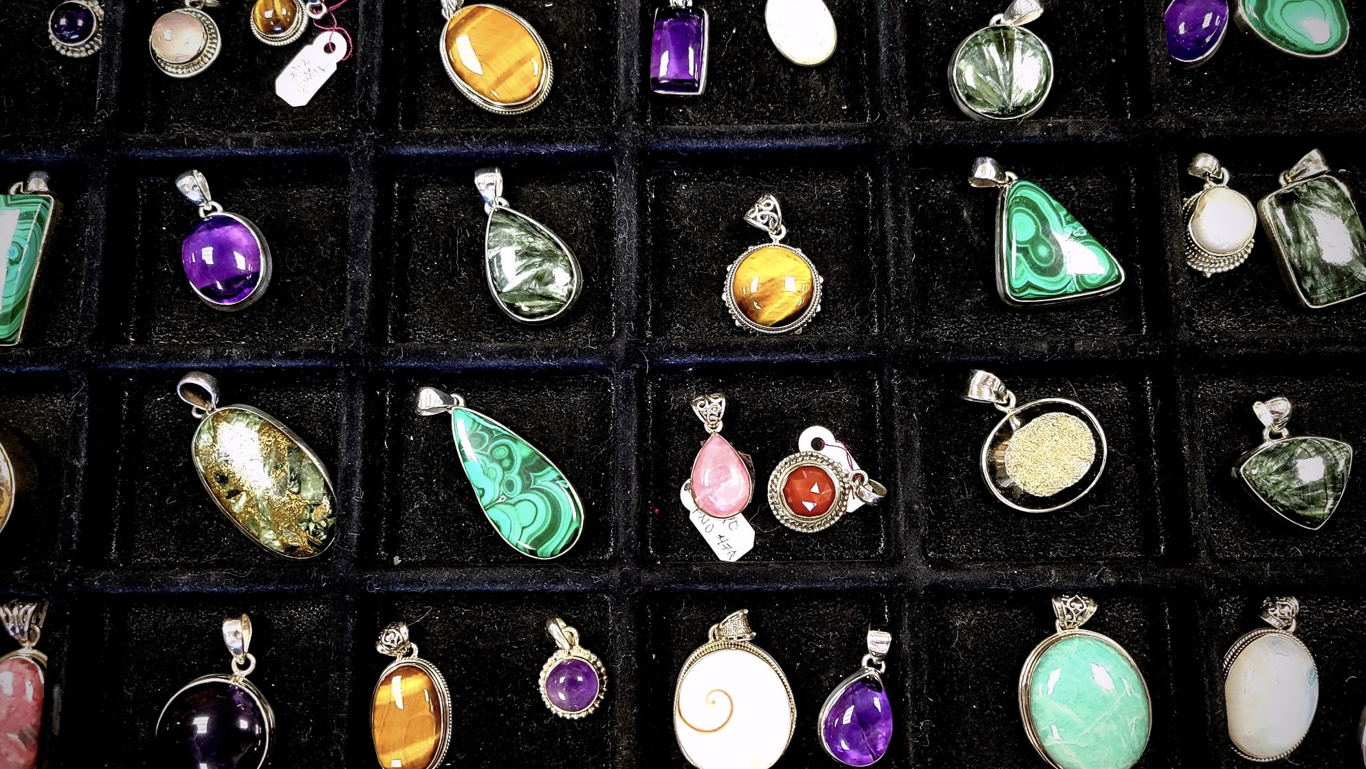 image of many small pendants made from rocks and minerals on a black background
