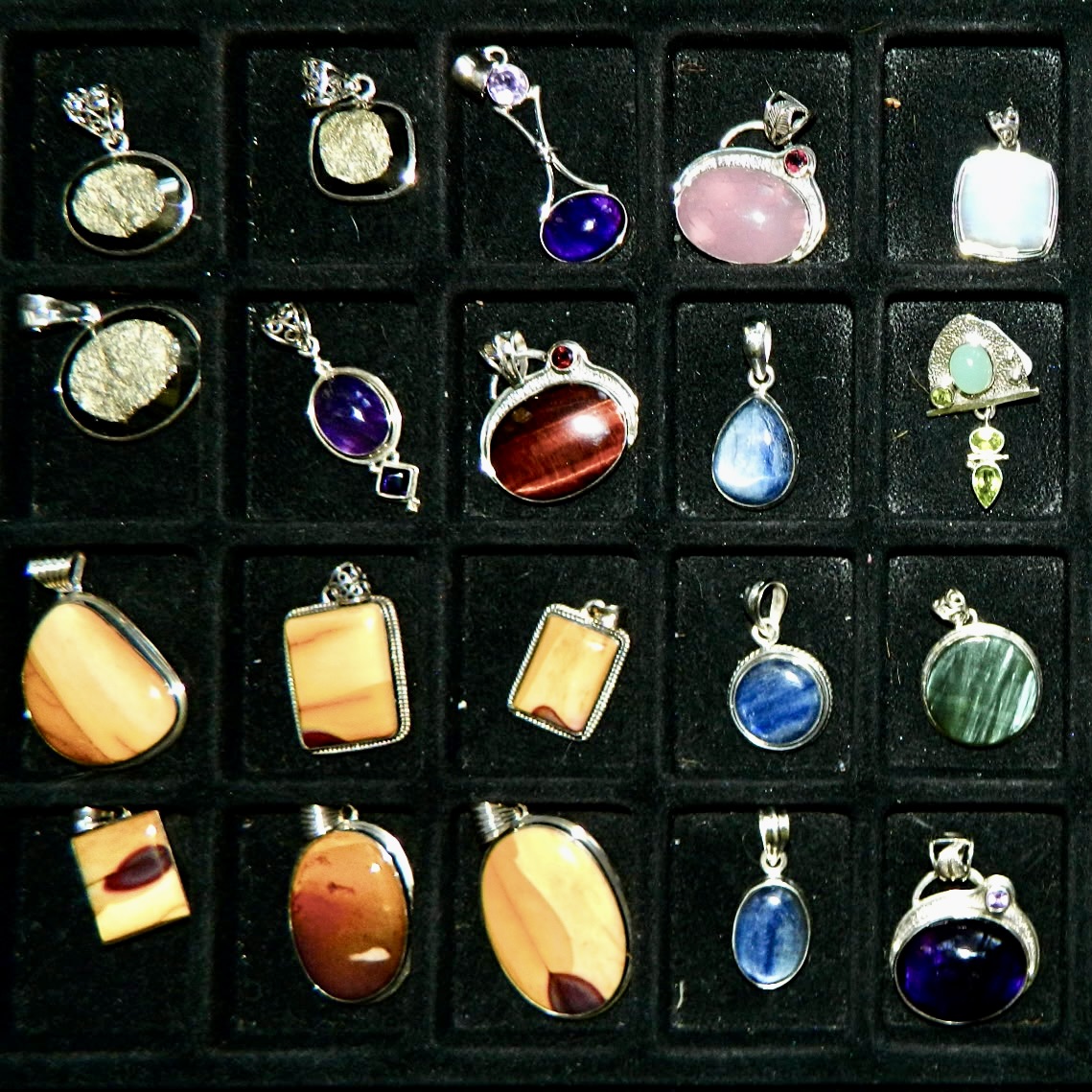 image of many small pendants made from rocks and minerals on a black background